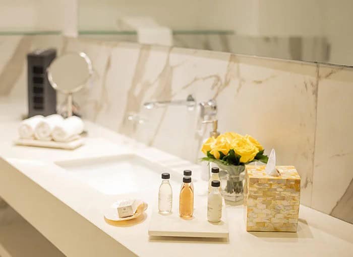 Baño elegante con artículos de tocador y flores frescas.