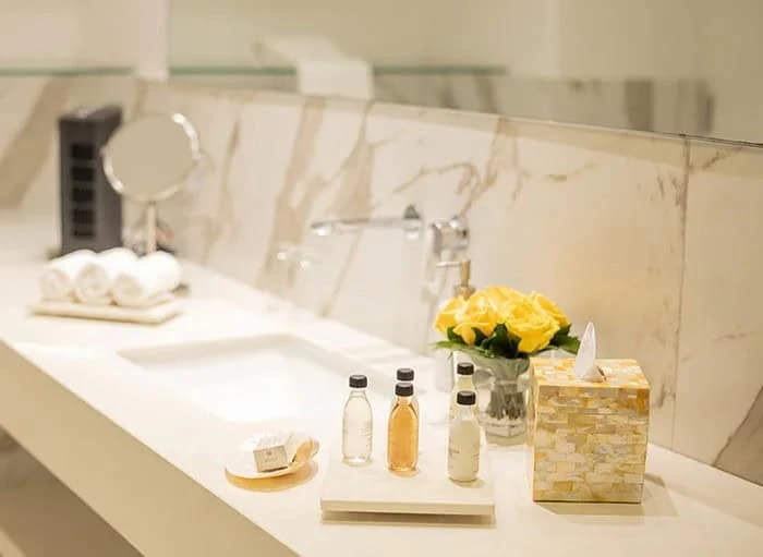 Baño elegante con artículos de tocador y flores frescas.